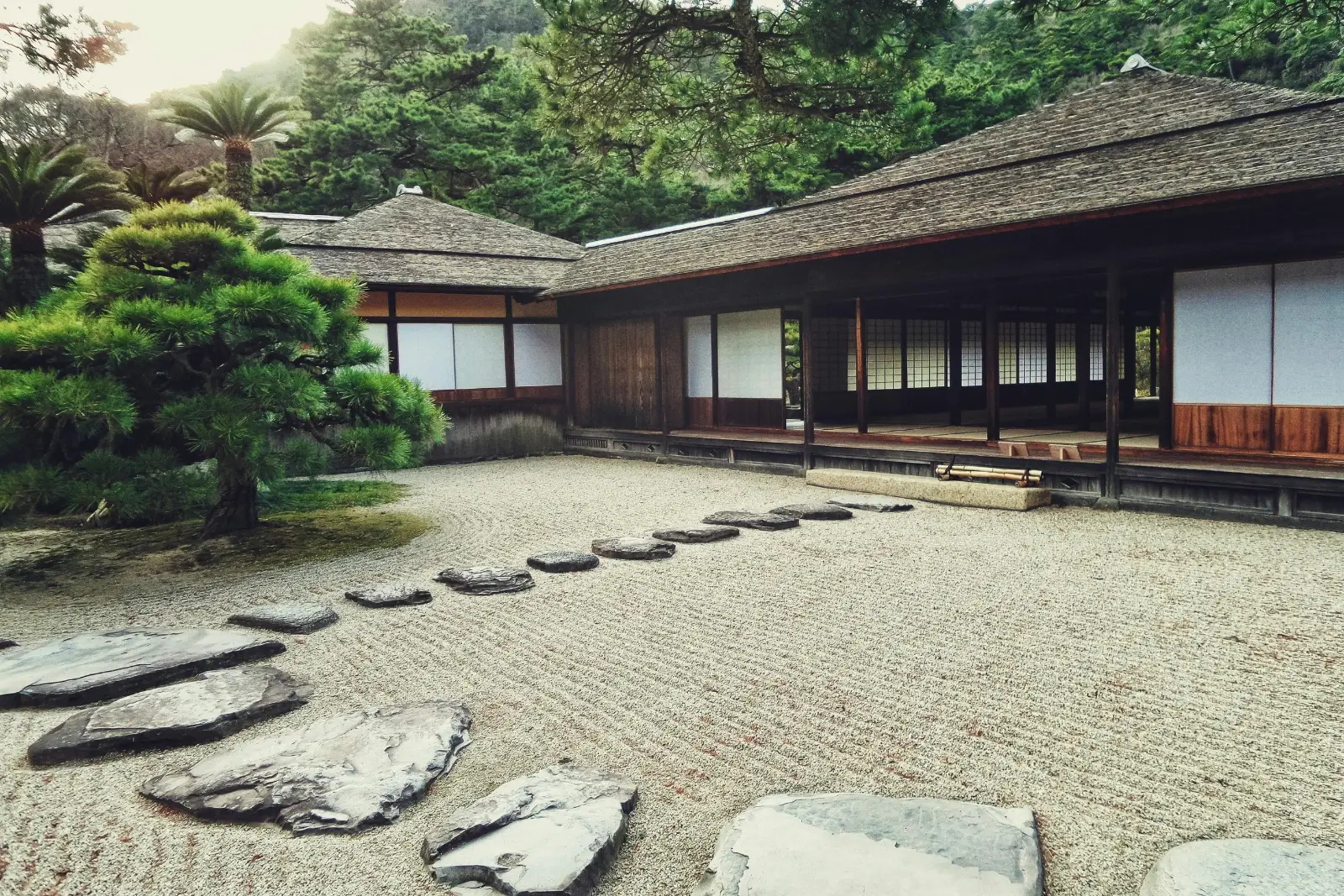 jardin japonais avec galets, maison, arbres.