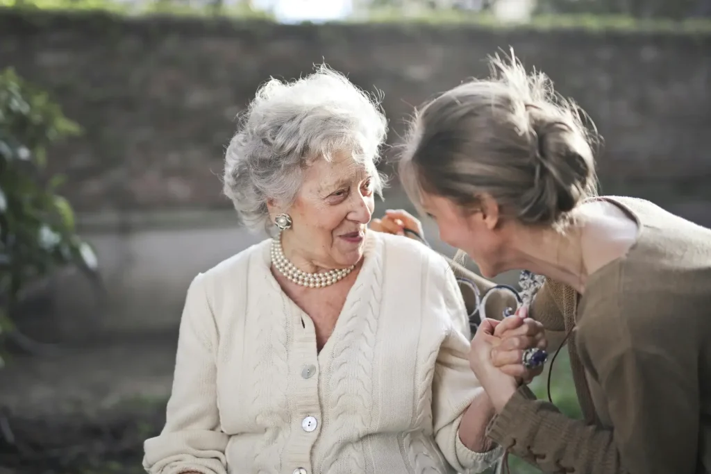 Deux femmes assises. Une de face souriant et l'autre de 3/4.