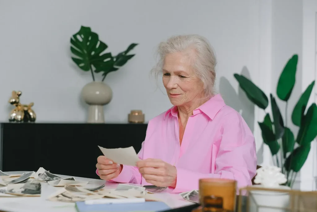 Personne âgée assise sur une table et lisant un papier.