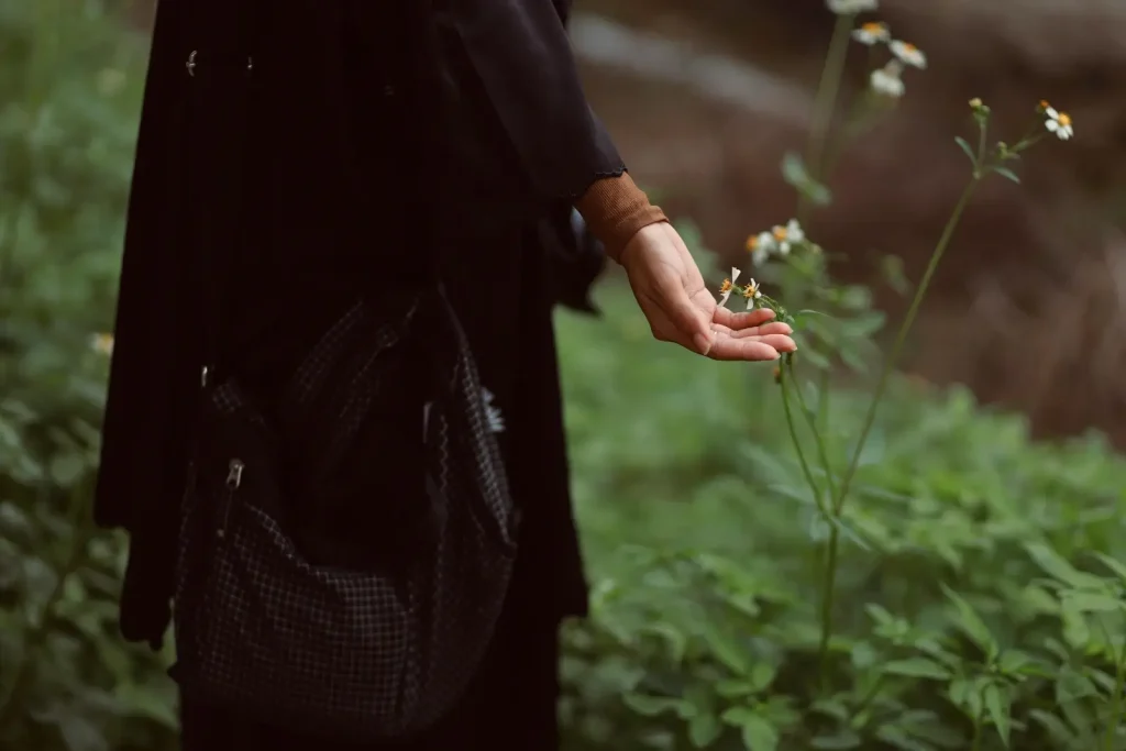 Personne dans un jardin, effleurant une fleur.