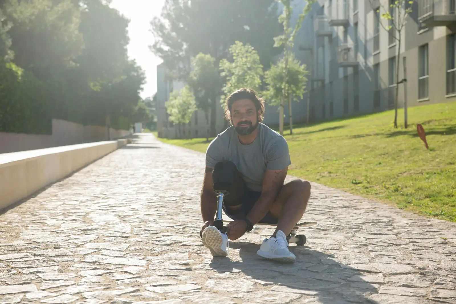 Personne paraplégique assise au sol sur une allée.