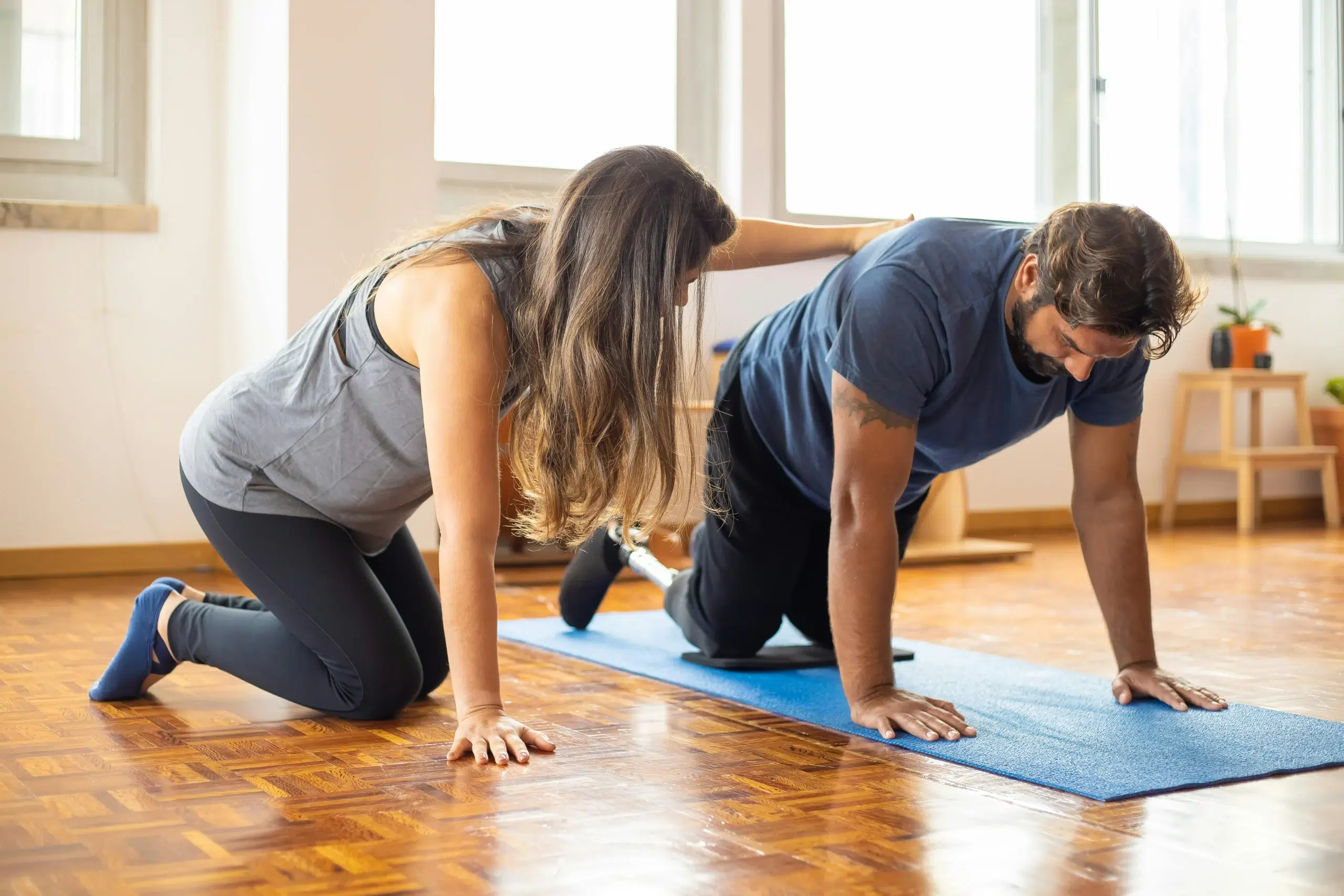 Personne avec handicape sur un tapis au sol avec une personne qui le soutien