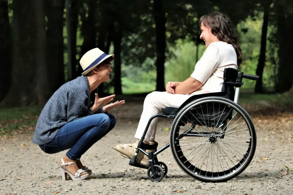 Une personne en fauteuil roulant et une autre accroupi devant elle.