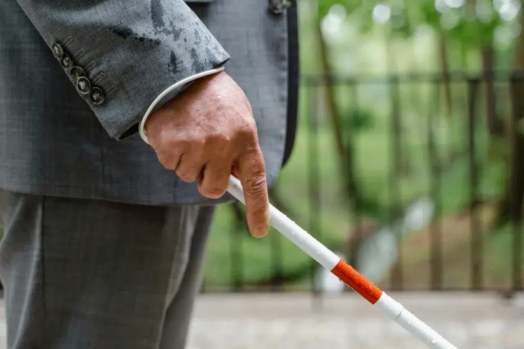 Personne avec un handicap sensoriel, un baton dans la main pour s'orienter.