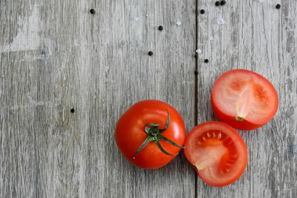 Tomates fraîches entières et coupées sur une table en bois, illustrant les bienfaits tomates pour la santé grâce à leur richesse en antioxydants.